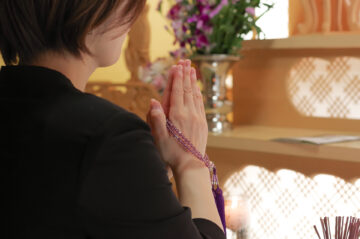 祭壇の前で合掌をして故人を弔う女性